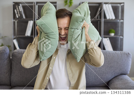 Stressed tenant blocking noise with cushions during neighbor disturbance at home 134311386