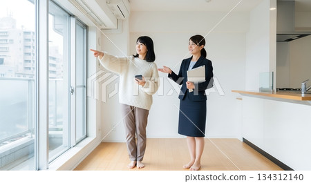 一位女士正在看一間公寓，一位房地產經紀人帶她參觀。 134312140