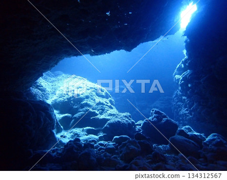 A view of light shining through a crevice in the rocks from inside an underwater cave A view of light shining through a crevice in the rocks from inside an underwater cave 134312567
