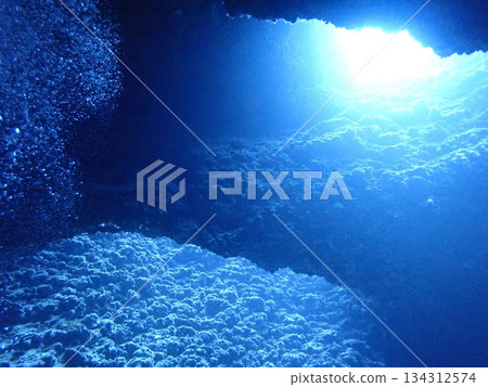 A view of light shining through a crevice in the rocks from inside an underwater cave A view of light shining through a crevice in the rocks from inside an underwater cave 134312574