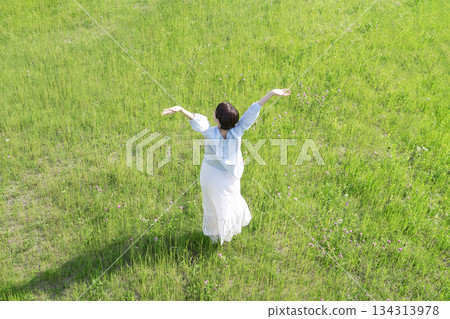 Woman taking a deep breath in the field, overhead view, back view Woman taking a deep breath in the field, overhead view, back view 134313978