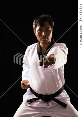 Strong male martial artist in Taekwondo uniform and black belt performing a powerful punch in studio, symbolizing confidence, precision, and self-defense technique Strong male martial artist in Taekwondo uniform and black belt performing a powerful punch in studio, symbolizing confidence, precision, and self-defense technique 134315123