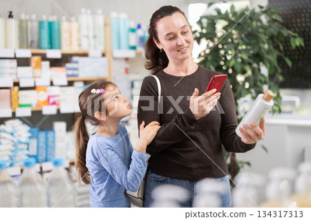 Woman scanning barcode on shampoo bottle 134317313
