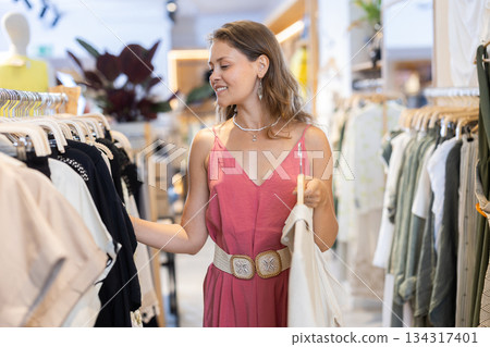 Young woman choosing shirt in clothing store 134317401