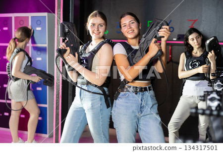 Two woman in the special vests holding laser guns and playing laser tag with girlfriends on bachelorette Two woman in the special vests holding laser guns and playing laser tag with girlfriends on bachelorette 134317501