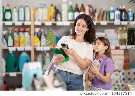 Woman and girl clients, by scanning QR code, gain access to information about dishwashing detergent 134317514