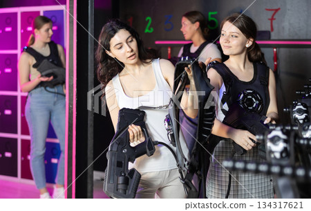 Young women choose protective equipment and uniforms before playing laser tag 134317621