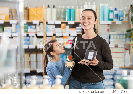 Woman with schoolgirl daughter are busy choosing face cosmetic at pharmacy 134317831