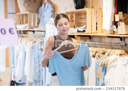 Young woman choosing blouse in clothing store 134317876
