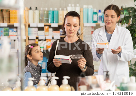 woman with a child buys medicines at a pharmacy with a pharmacist woman with a child buys medicines at a pharmacy with a pharmacist 134318019