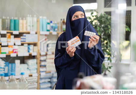 Young Muslim woman customer choosing pills in box in drugstore 134318026