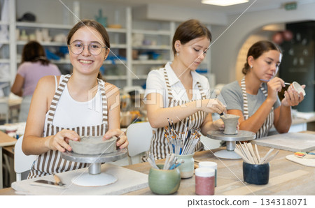 Woman teacher and students sculpt and paint ceramics Woman teacher and students sculpt and paint ceramics 134318071