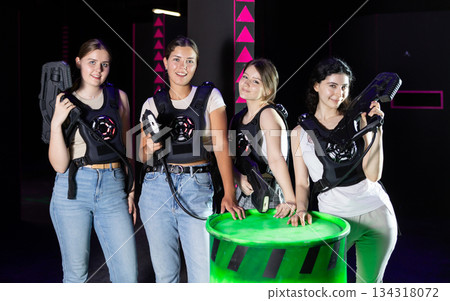 Four cheerful and happy girls pose in locker room before laser tag match. Four cheerful and happy girls pose in locker room before laser tag match. 134318072