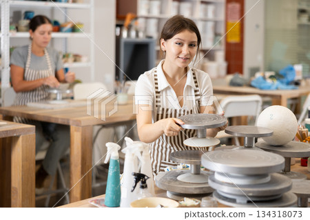 Young girl puts pottery wheel for clay modeling Young girl puts pottery wheel for clay modeling 134318073