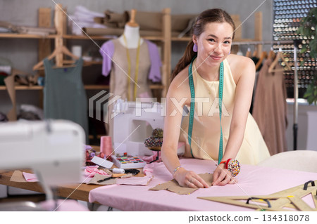Young female seamstress attaching template to fabric 134318078