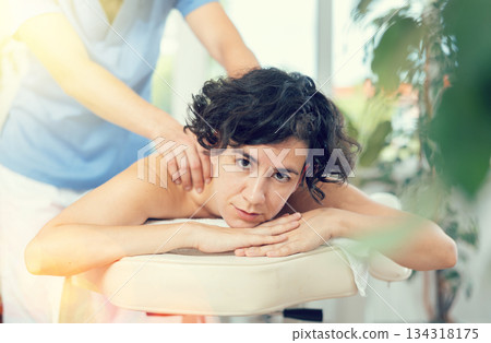 Portrait of young female which is lying on massage table in spa Portrait of young female which is lying on massage table in spa 134318175