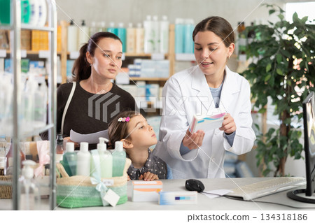 Woman pharmacist using computer during family consulting Woman pharmacist using computer during family consulting 134318186