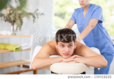 Masseuse doing back massage to young guy 134318220