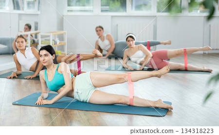 Group of women training leg muscles using resistance bands during Pilates class Group of women training leg muscles using resistance bands during Pilates class 134318223