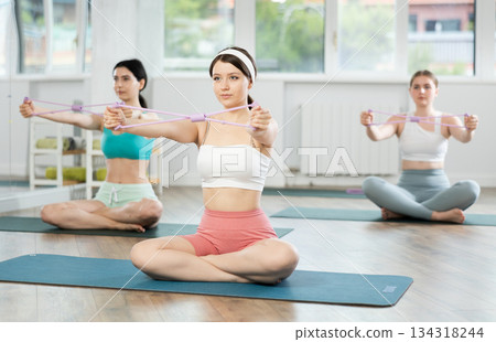 Group of young women doing pilates with loop Group of young women doing pilates with loop 134318244