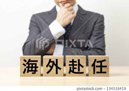 一塊寫著「海外派遣」字樣的磚塊和一個商人 134318419