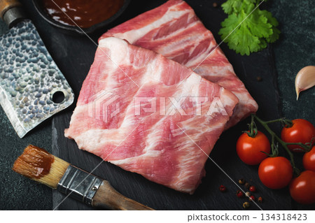 Raw meat. Raw pork ribs from the back with meat on a black background. background image Raw meat. Raw pork ribs from the back with meat on a black background. background image 134318423