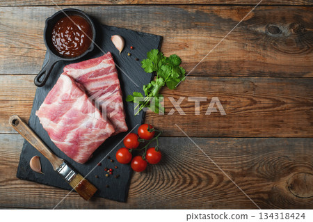 Raw pork ribs with spices, salt and rosemary on dark wooden background Raw pork ribs with spices, salt and rosemary on dark wooden background 134318424