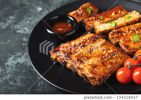 Hot grilled spare ribs from a summer BBQ served on a plate with sauce. Top view. Copy space Hot grilled spare ribs from a summer BBQ served on a plate with sauce. Top view. Copy space 134318437