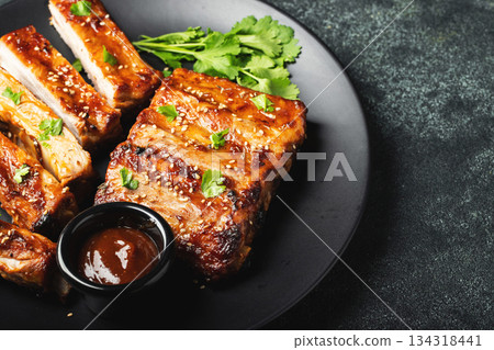 Hot grilled spare ribs from a summer BBQ served on a plate with sauce. Top view. Copy space 134318441