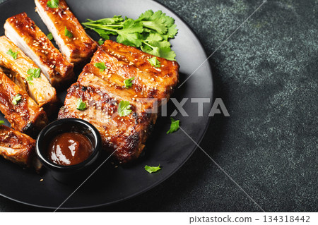 Hot grilled spare ribs from a summer BBQ served on a plate with sauce. Top view. Copy space 134318442