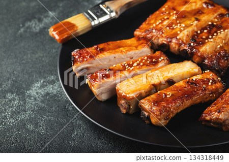 Hot grilled spare ribs from a summer BBQ served on a plate with sauce. Top view. Copy space 134318449