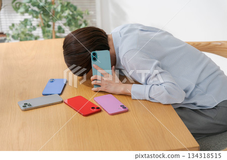 一位情緒低落的女士被許多智慧型手機包圍著。 134318515