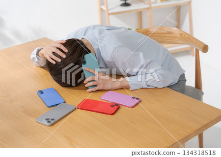 A woman feeling depressed surrounded by many smartphones A woman feeling depressed surrounded by many smartphones 134318518