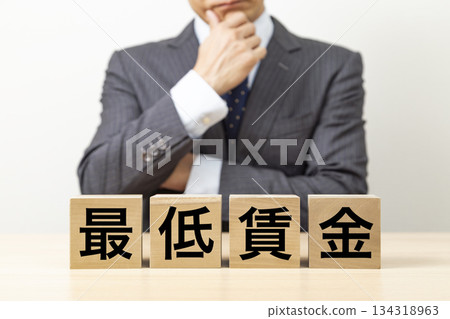 A block with the word "minimum wage" written on it and a businessman A block with the word "minimum wage" written on it and a businessman 134318963