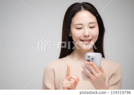 Portrait of a beautiful woman using a smartphone. Cute selfie taking photos in the mirror or live streaming. 134319796
