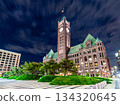 Minneapolis City Hall stands in downtown Minneapolis, USA. Historic Richardsonian Romanesque building features a clock tower and green copper roof at night 134320645