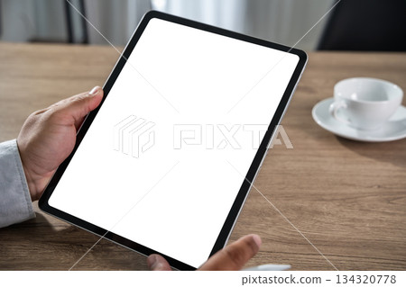 A businessman holds a mockup. iPad digital tablet with blank screen Mockup replaces your design mockup in the office. 134320778