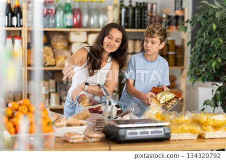 Teenage son and mother choose different products together in grocery supermarket 134320792
