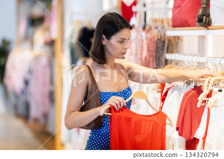 Young woman standing in store and choosing clothes 134320794