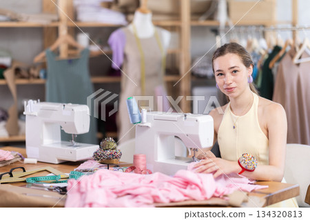 Seamstress working on modern sewing machine in sewing workshop Seamstress working on modern sewing machine in sewing workshop 134320813