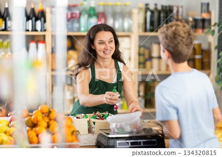 Female seller weighs candies for boy buyer Female seller weighs candies for boy buyer 134320815