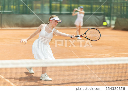 Female athlete plays tennis on open court 134320856