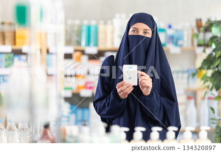 Young Muslim woman customer choosing pills in box in drugstore Young Muslim woman customer choosing pills in box in drugstore 134320897