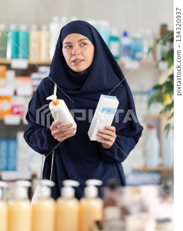 Young woman in hijab chooses cream at pharmacy Young woman in hijab chooses cream at pharmacy 134320937
