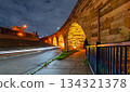 Stone Arch Bridge features illuminated arches at night in Minneapolis. Long exposure captures light trails on West River Parkway under a cloudy sky 134321378