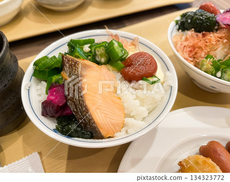 Grilled salmon and pickled plums served on top of freshly cooked rice in a bowl at the breakfast buffet. 134323772