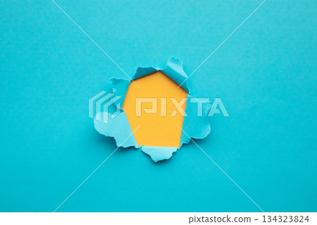 Torn ripped blue paper hole on yellow background Torn ripped blue paper hole on yellow background 134323824