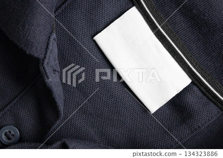 Blank white laundry care clothes label on black shirt fabric texture background 134323886