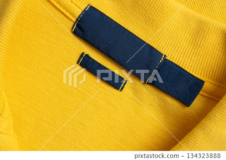 Blank blue laundry care clothes label on yellow shirt fabric texture background 134323888