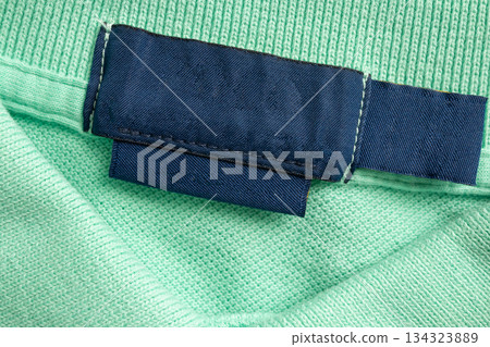Blank blue laundry care clothes label on green shirt fabric texture background 134323889